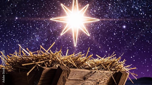 Bright shining star above empty wooden manger with hay on starry night sky background