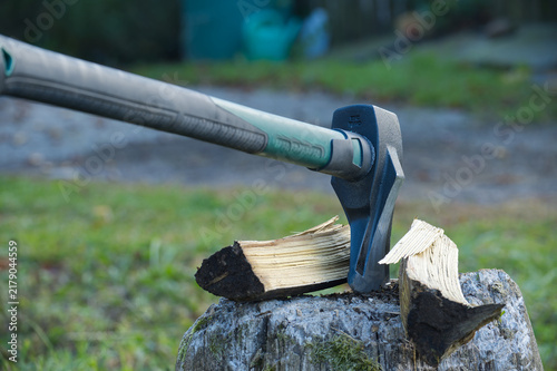 Axe splitting wood on a tree stump, a close view of the tool in action outdoors.