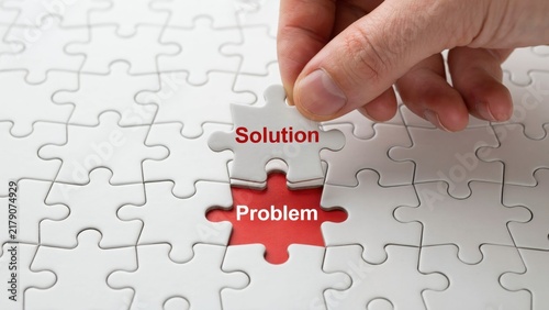 Canvas Print Human hand placing a white jigsaw puzzle piece labeled solution over a red base