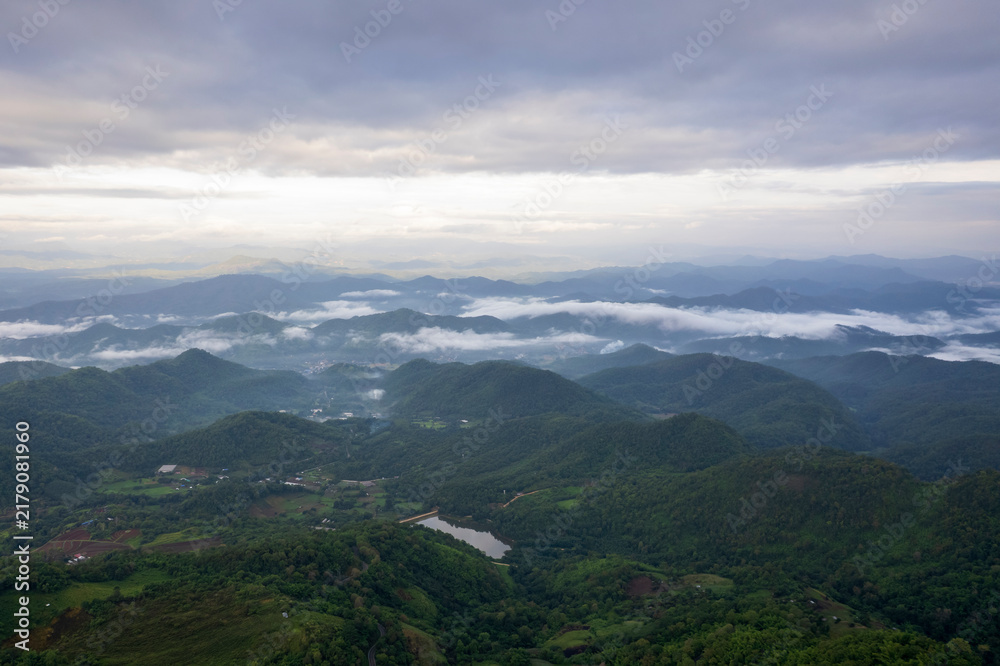 Fototapeta premium Landscape of Morning Mist with Mountain Layer. mountain ridge and clouds in rural jungle bush forest