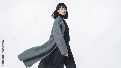 Fototapeta グレーのロングコートを着て颯爽と歩く黒髪の日本人女性
