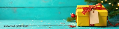 Yellow gift box, turquoise wood backdrop, festive ribbon and tag , holiday, view