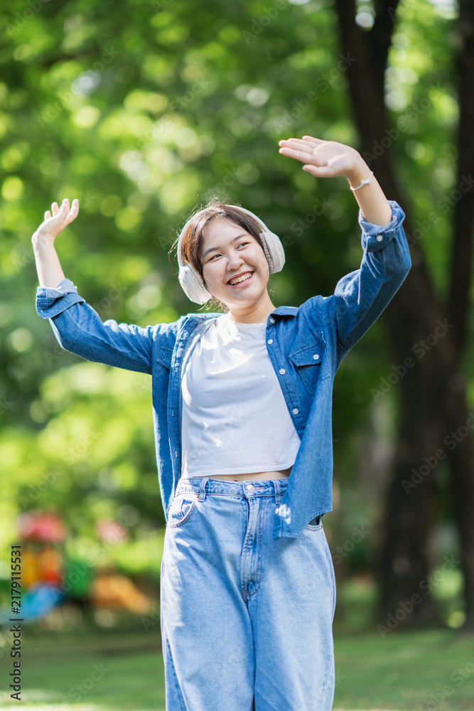 Obraz premium Happy young asian woman dancing with headphones outdoors