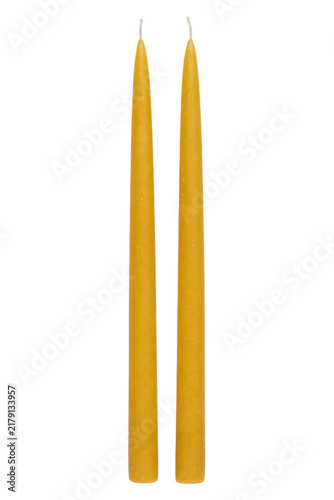 Fotografie Two tall, slender, yellow beeswax taper candles with white wicks stand upright o