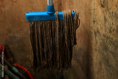 A photo of a worn-out mop or floor cleaner hanging in the bathroom.