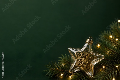 歯車を閉じ込めた透明な星飾りとモミの枝のクリスマス背景