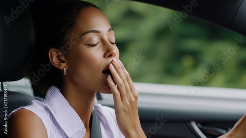 Young woman yawning while seated inside moving car