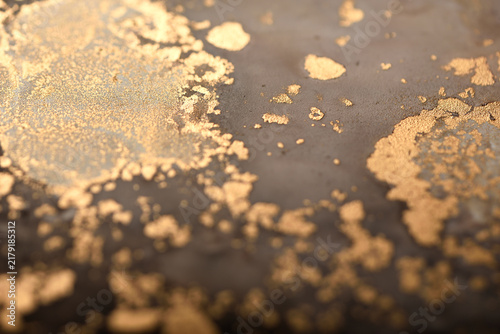 Artistic background with dark brown and gold swirls; photo of the surface.