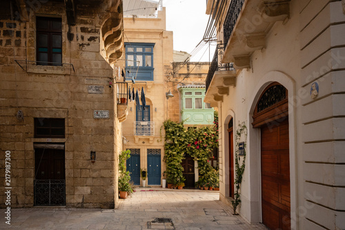 Фотография Sunlit cobblestone street with colourful Maltese balconies