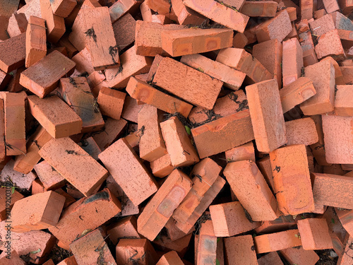 Pile of scattered red clay bricks for construction material background