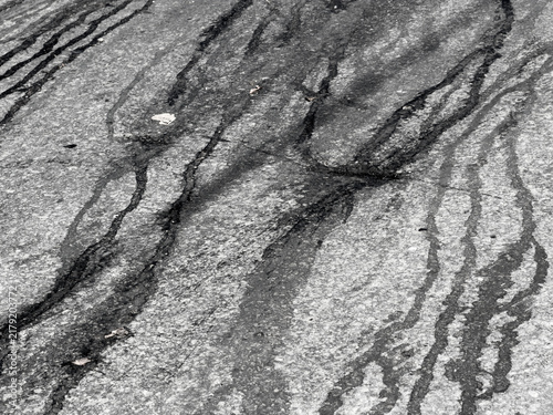 Abstract patterns of dark streaks on textured, grayish ground surface