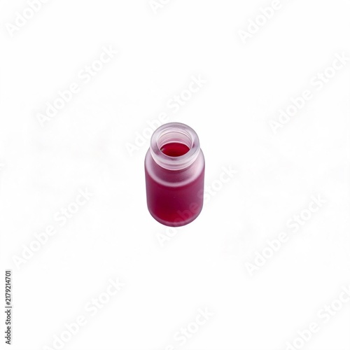 Small open glass bottle filled with vibrant red liquid isolated on a plain white background with miniature frosted glass solution fresh pressed elixir 