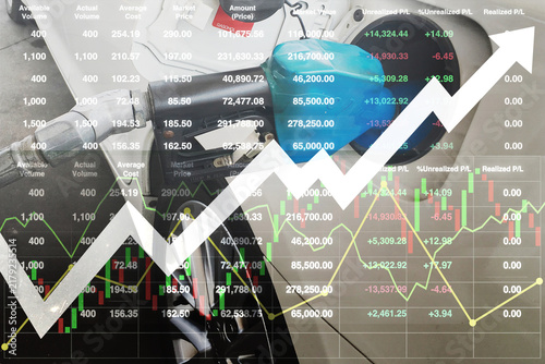 A close-up shot of a blue fuel nozzle dispensing gasoline into a car, seamlessly double-exposed with a financial stock trading interface. The composition features stock market price data tables.