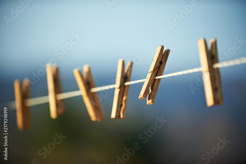 Wooden Clothespins Hanging on Clothesline Against Blue Sky Outdoor Background