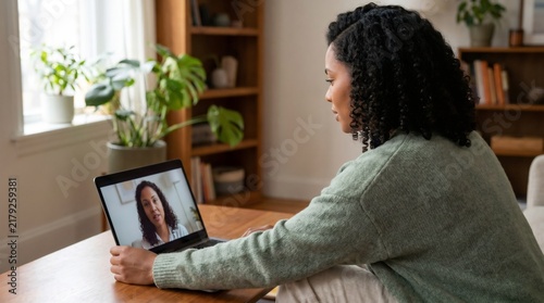 Young woman attending online therapy session via video call on laptop at home