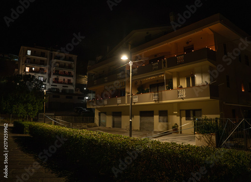 night view of residential apartment buildings illuminated by street lamps with balconies and surrounding greenery