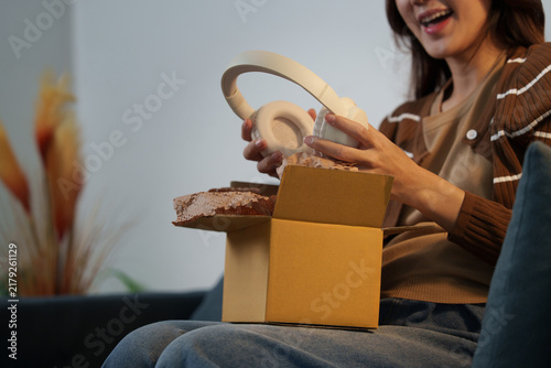 Woman unboxing wireless headphones from cardboard package for online shopping concept