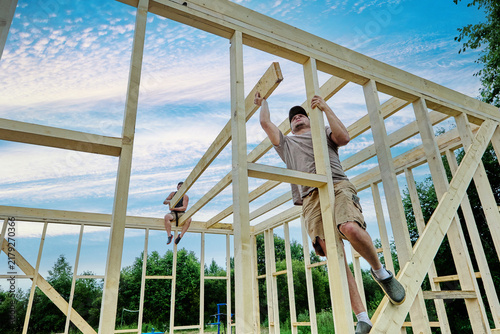Konstfotografi Builders lift and position ceiling beams, integrating them into framework of timber frame house