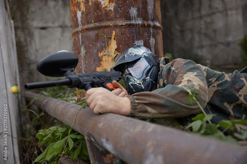 Obraz premium A soldier aims a gun while leaning on a pipe, lying on the ground