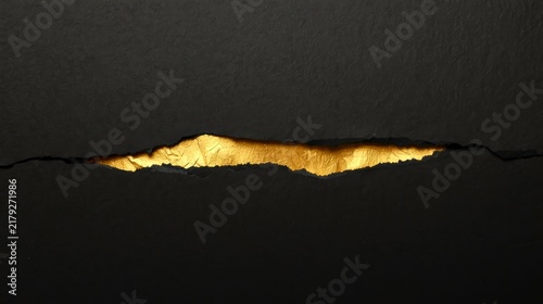 Black paper torn open reveals gleaming gold beneath