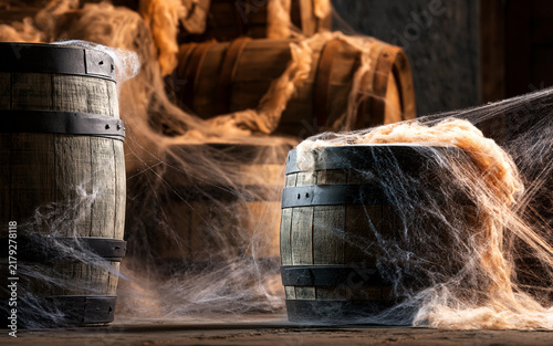 Halloween spooky decoration in an old winery or distillery, cobwebs and barrels for a haunted house theme