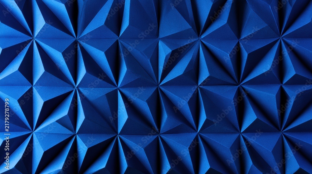 Fototapeta premium The image shows a blue origami folded surface with geometric facets designed on a paper-like backdrop. There is space for text.