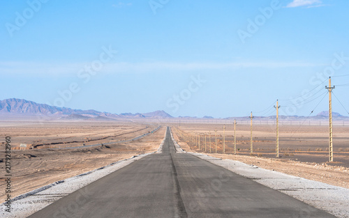 Straight desert road towards mountains near Naein, Iran