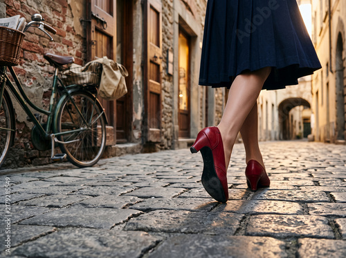 Red high heels walking on cobblestone street near a bicycle  