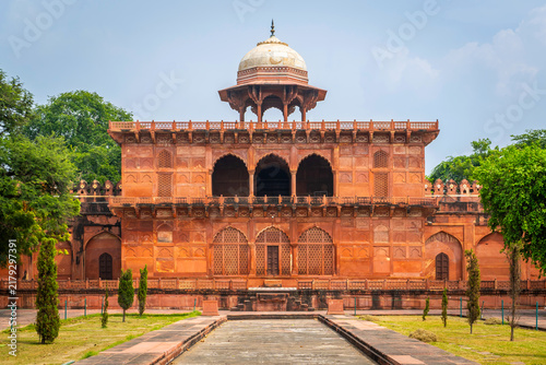 Historic red sandstone pavilion topped with a marble dome pavilion surrounded by lush green trees and pathway at the Taj Mahal complex in Agra, Uttar Pradesh, India.