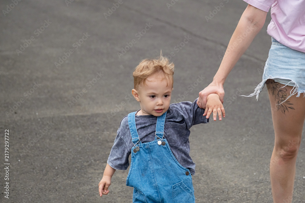 Fototapeta premium Mother pulling stubborn toddler boy by hand on street.