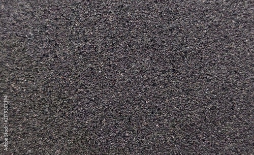 Fotografie Macro view of a dark asphalt road surface featuring fine gravel aggregate and a rugged, textured pattern, creating a seamless pavement background