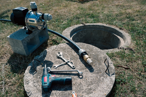 Cuadro en lienzo Tools and suction pipe with brass check valve lying on concrete well cover next