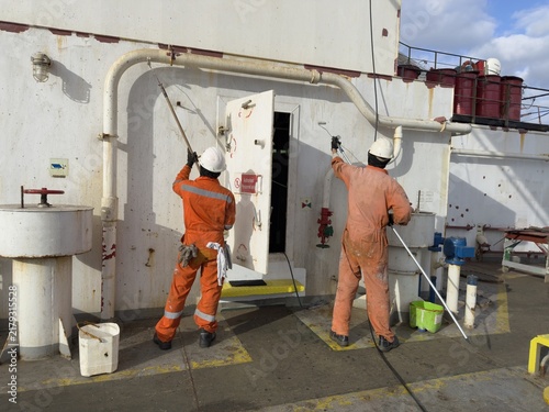 Fotografie crew members painting aft part of ship superstructure.