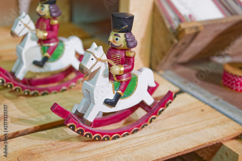 Traditional wooden nutcracker soldier toy riding white rocking horse on wooden surface