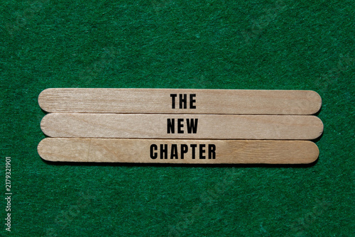 Foto Wooden sticks arranging the words the new chapter on a vibrant green felt backgr