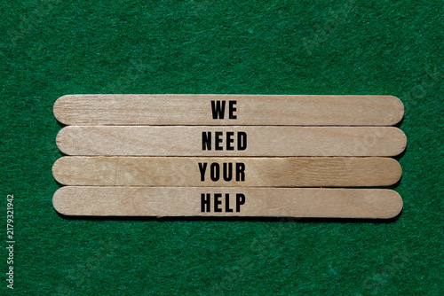 Obraz na płótnie Wooden craft sticks displaying the words we need your help, conveying a strong m