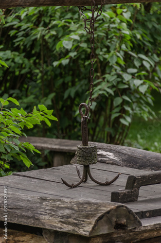 Vintage wooden well with rusty iron chain and triple hook