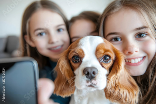 Smiling children take selfie with a dog in a cozy indoor setting