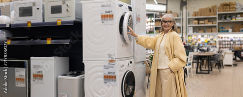 Senior woman smiling, choosing a washing machine in a large electronics store