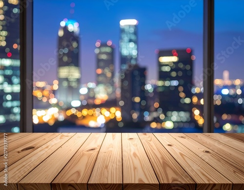 Wooden tabletop overlooking blurred, lit cityscape through large window at twilight