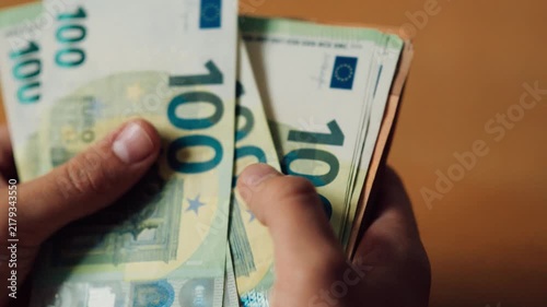 Person counting euros in hands at a table in a bright indoor setting during the day