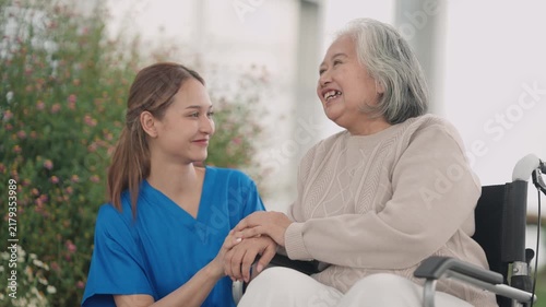 Caregiver walking with senior in wheelchair outdoors