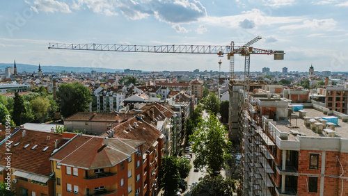 Aerial view of a construction crane towering over residential buildings and rooftops in the city of Novi Sad, Vojvodina, Serbia.