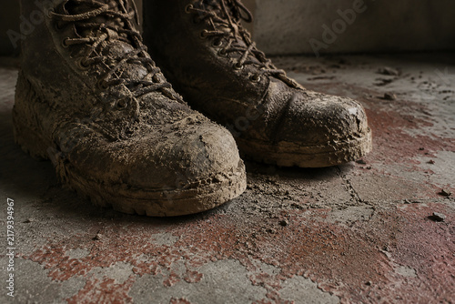 Pair of muddy work boots on concrete floor, labor and endurance concept