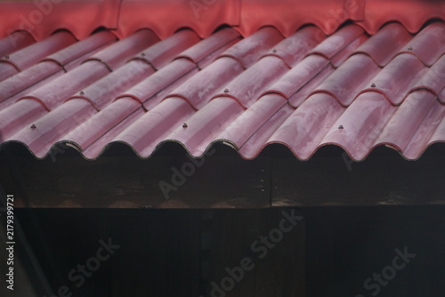 Foto Close-up perspective of wavy red composite roof tiles showing architectural overlapping lines and weathered outdoor surfaces