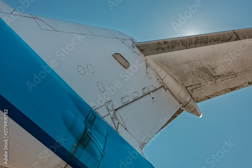 Фотография Backlit view from below of the tail root and horizontal stabilizer of a parked airliner, with the sun flaring behind the tail surface