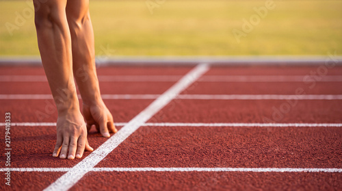 Runner hands on starting line ready to sprint on red running track