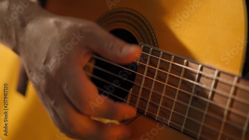 Playing Guitar. Musician Strumming On Strings By Hand On Acoustic Guitar. Close-up. Warm Cozy Light Highlights The Wooden Music Instrument. Man musician playing an acoustic guitar