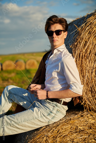 Foto Relaxed man sitting beside hay bale