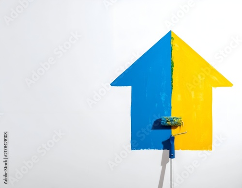 A house shape is half-painted blue, half-yellow with roller resting on yellow